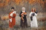 Three girls holding foxes in the woods.