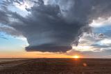 Tornadic storm supercell rotates and marches along the Texas prairie at sunset